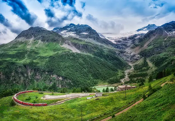 Red train Bernina Express to the passage in the mountains in the summer