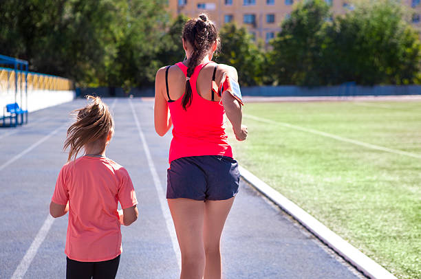 母と小さな娘はスタジアムで運動をしています - running track women running spring ストックフォトと画像