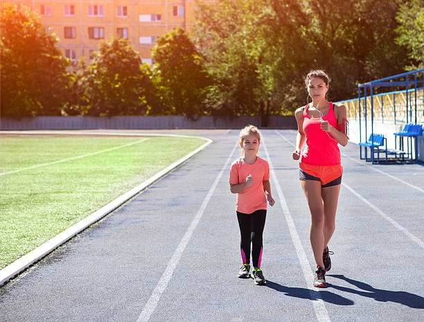 madre e hija pequeña hacen ejercicio en el estadio - running track women running spring fotografías e imágenes de stock