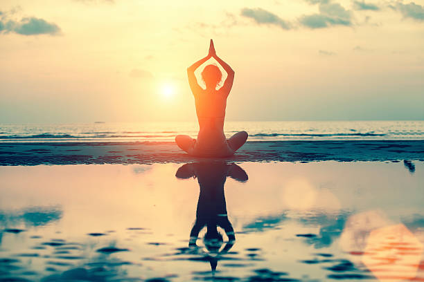 istock Silhouette young woman practicing yoga on the beach at sunset. 586920300