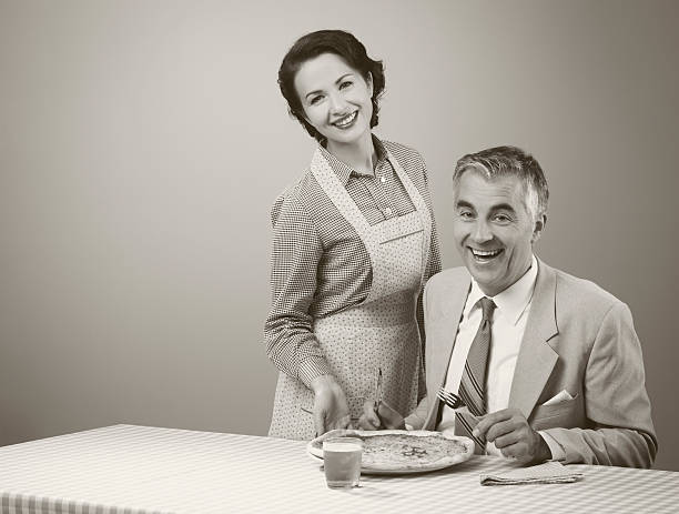 sorridente moglie servire la cena - stereotypical homemaker foto e immagini stock