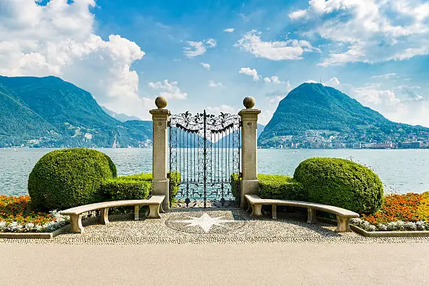Lugano city on Lake Lugano in the Swiss canton of Ticino, Switzerland.  It is located at the foot of the Swiss Alps. This picture shows Lugano city from city park with lake and mountains.