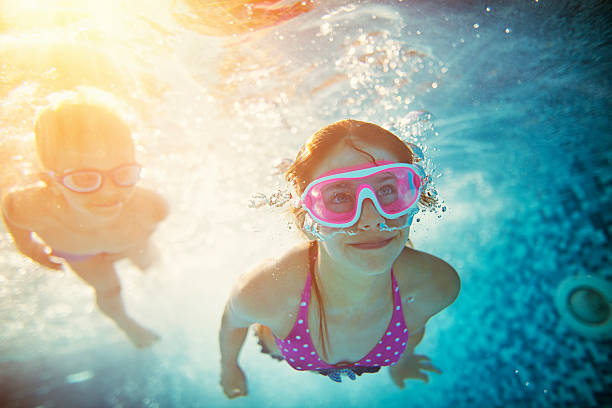 istock Happy kids swimming underwater in pool 586928530
