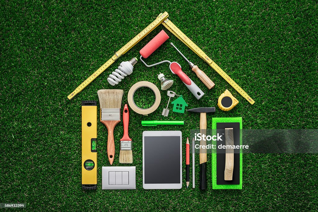 Home renovation and DIY Home renovation, remodeling and DIY concept, work tools and tablet composing a house shape on the grass Repairing Stock Photo