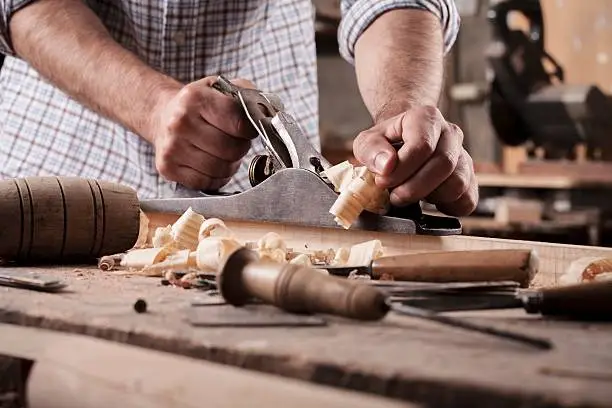 carpenter working with plane on wooden background