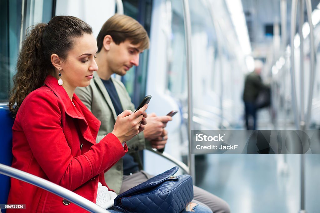 Young passengers in subway car Happy young passengers with baggage and phones in a subway car Map Stock Photo