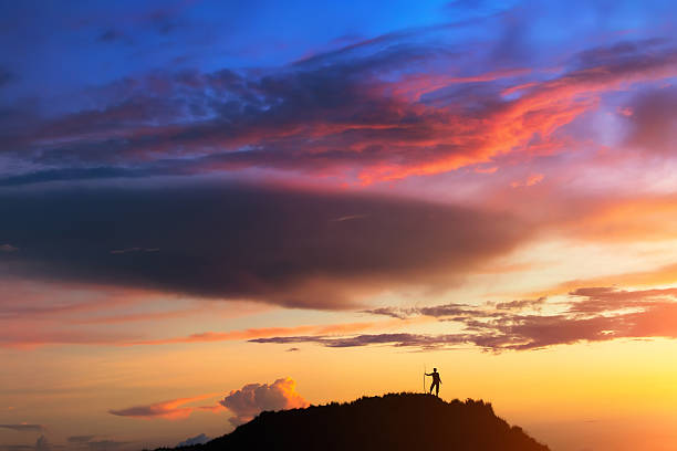 A person is standing on the hill beneath colorful sky at the sunset. Clicked on the top of Batur volcano (Bali, Indonesia).