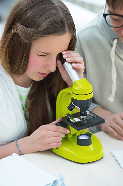 istock High School students. Beautiful girl looking through microscope 586938472