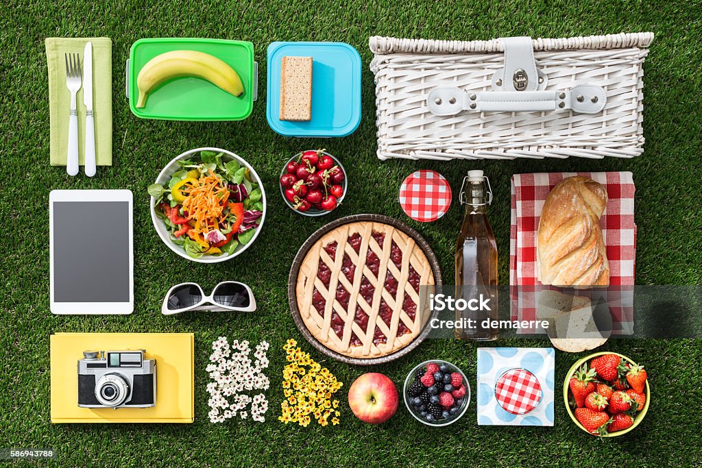 Picnic on the grass Summertime picnic on the grass with basket, salad, fruit and accessories, flat lay Picnic Stock Photo