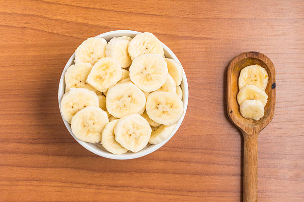 istock Banana slices into a bowl over a wooden table 586944300