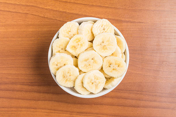 istock Banana slices into a bowl over a wooden table 586944452