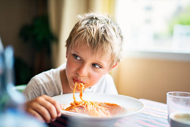 mignon petit garçon mangeant des spaghettis - child eating pasta spaghetti photos et images de collection