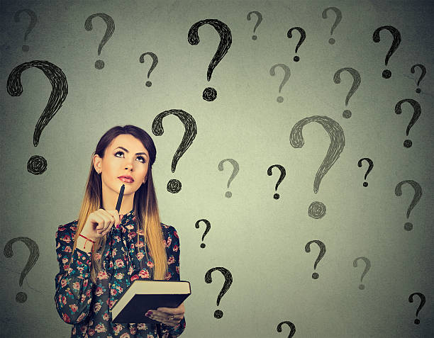 istock Thinking woman looking up at many questions mark 586948240