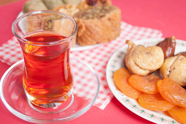 Turkish delight in a plate, glass cup of tea and dried fruit on red background. Eastern delight. baklava, burma baklava, Mebrume.