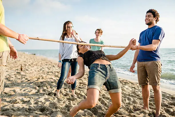 group of people playing limbo on the beach