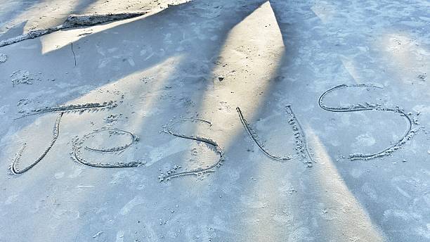 istock Jesus NameText Written in Beach Sand 587184824