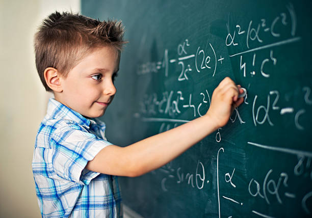 netter kleiner junge, der schwierige mathematische probleme löst - mathematics mathematical symbol child intelligence stock-fotos und bilder