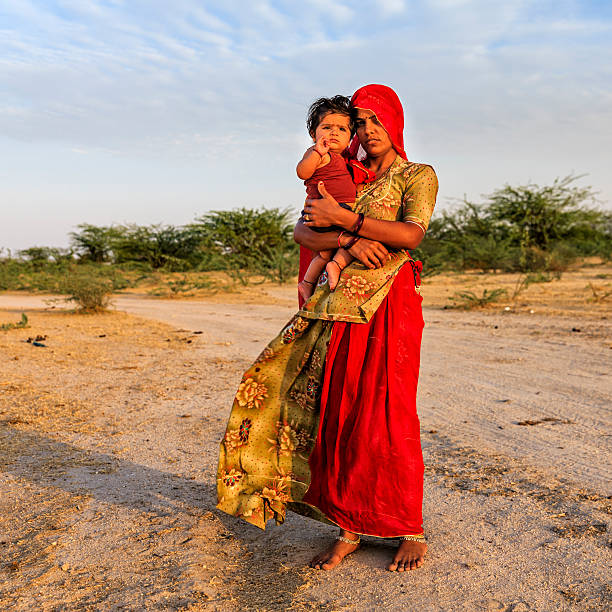 junge indische frau hält ihr kleines baby, indien - poverty india child little girls stock-fotos und bilder
