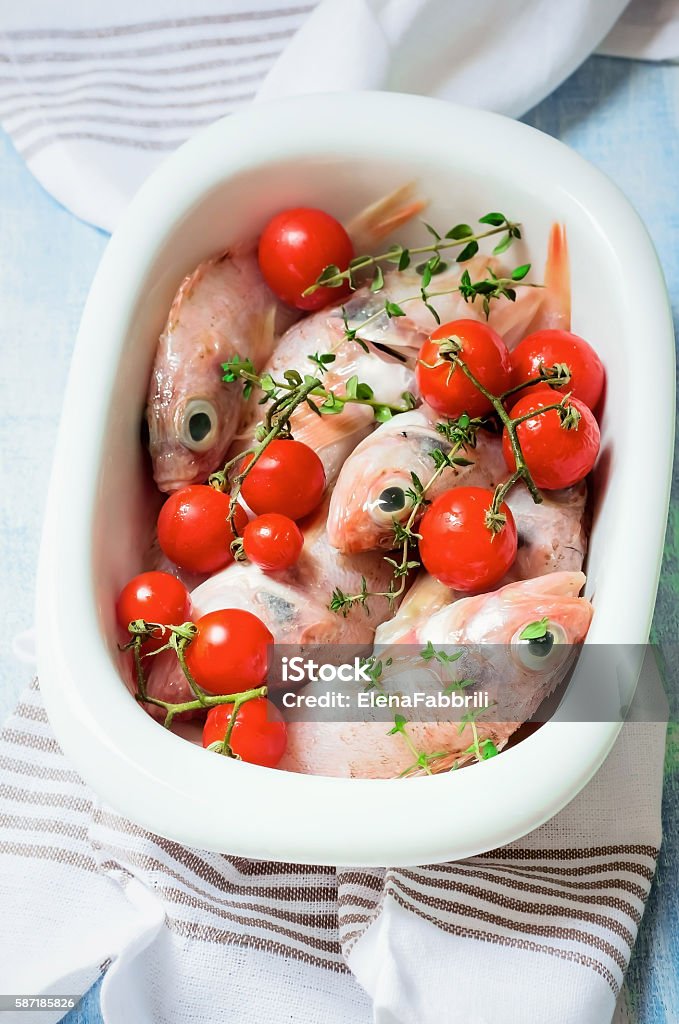 Raw fish (Sea-bass, Sea bream) with cherry tomatoes and thyme Prepared baking dish with red fish(Shimmering Ocean Perch), cherry tomatoes and thyme. Diet menu. Top view Baked Stock Photo