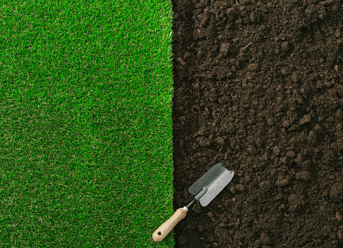 Gardening shovel on the fertile soil and grass, gardening and landscaping concept