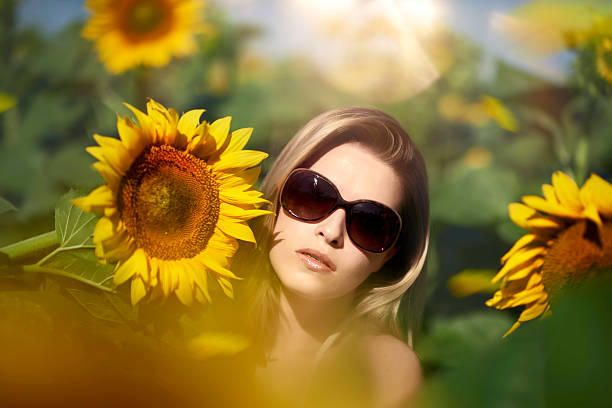 beautiful and relaxed blond hair woman in the nature surrounded by sunflowers and enjoying the summer.wearing sunglasses.