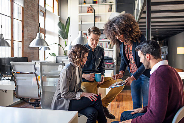 istock Young creative coworkers discussing project on digital tablet 587188008