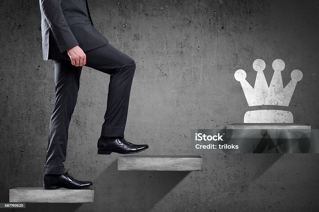 Businessman is climbing up to get crown Low section view of a businessman walking up staircase to get crown representing the concept of Successful business person. Business Person Stock Photo