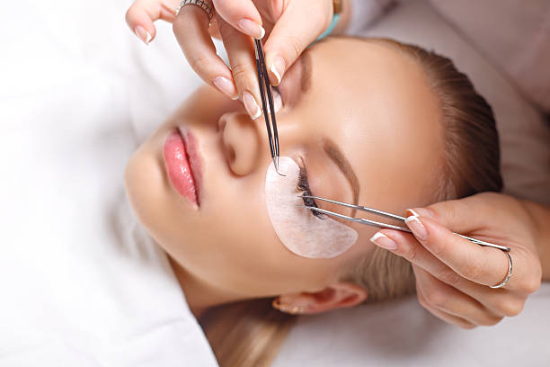 eyelash extension procedure. woman eye with long eyelashes. lashes. - make up women ceremonial makeup senior women imagens e fotografias de stock