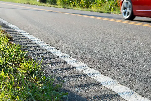 Grooved rumble strips, also called rumple stripes or sleeper lines, on the side of a two-lane highway in Carter County, Tennessee. The strips are a safety feature to alert drivers who are veering off the road.