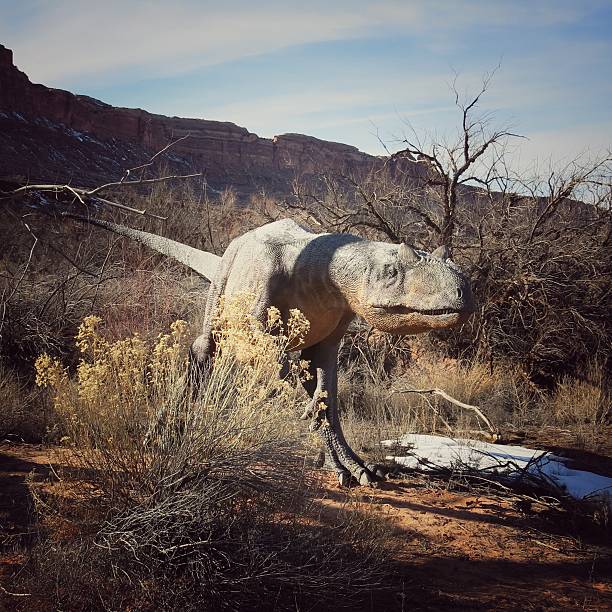 istock Dinosaur Figure Walking in Desert Snow Patch Landscape 587195242