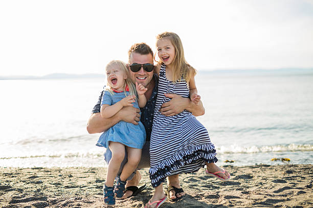 istock Father playing with two daughter at beach in a sunny 587195754