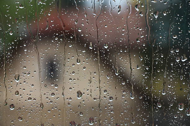 istock Rain drops on window with house and church in background 587197290