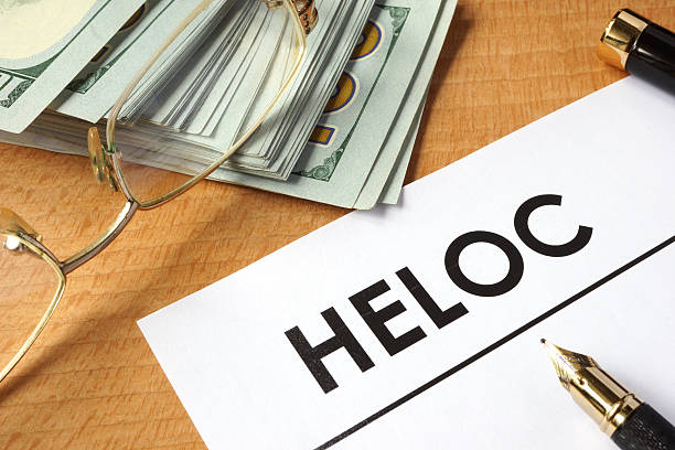 HELOC printed on a paper with pen, reading glasses, and cash