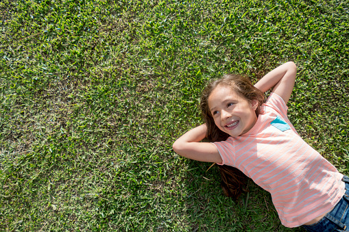 Beautiful Latin American girl relaxing at the park lying on the floor and smiling