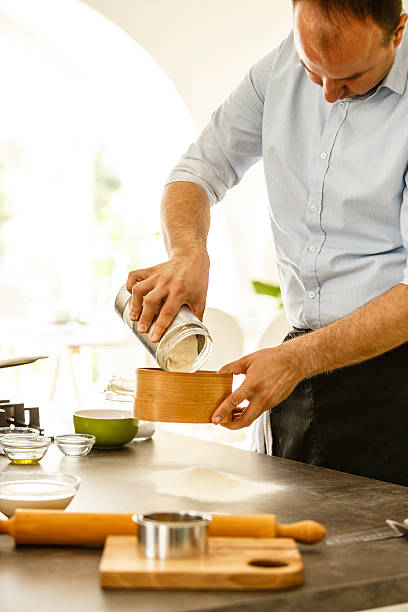 istock Man sieving flour on the kitchen counter, making dough 587201786