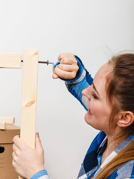 istock Woman assembling wood furniture using hex key. DIY 587203994