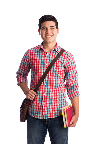 A young latin man smiling with a messenger bag and books in a vertical medium shot with white background.
