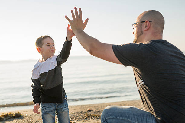 istock Son on father shoulders at the beach having fun  sunset 587205548