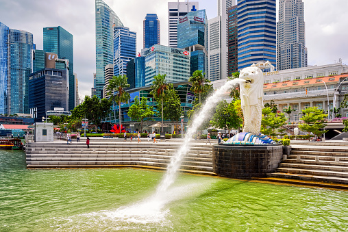 Singapore, Singapore - March 1, 2016: Merlion statue spraying the water from its mouth at Merlion Park in Downtown Core of Singapore at Marina Bay. Skyline of Skyscrapers on the background.