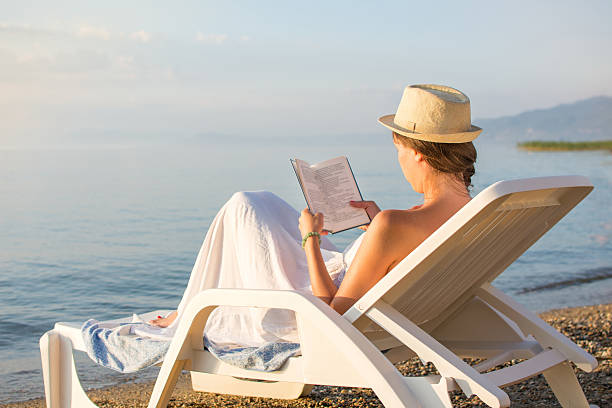 istock Girl reading a book in sunbed 587208486