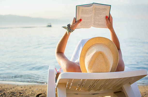 istock Girl reading a book in sunbed 587208916