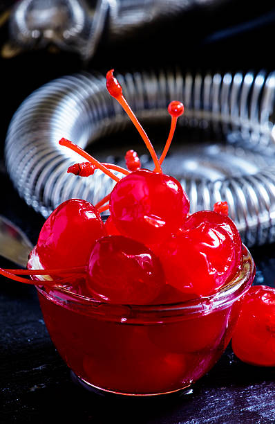 Red cocktail cherry, bar tools Red cocktail cherry, bar tools on a dark background, selective focus maraschino cherry stock pictures, royalty-free photos & images