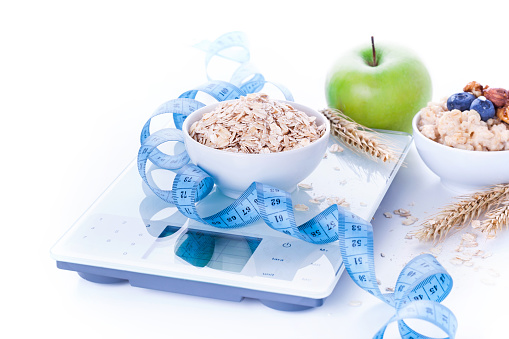 Electronic digital kitchen scale with oatmeal, apple and measuring tape. Healthy nutrition concept