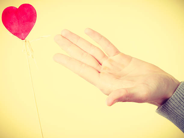 istock Male hand with little heart on stick. 587215870