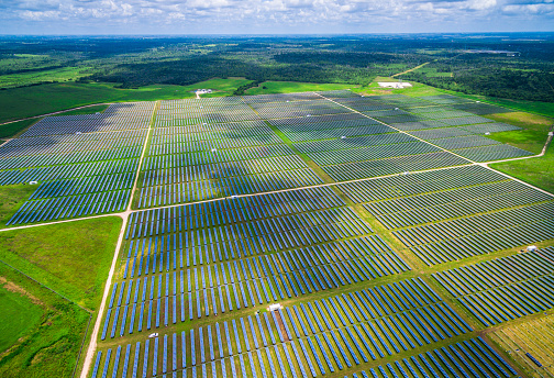 Central Texas Solar Energy Farm Aerial over thousands of Solar Collectors near webberville , Texas a massive solar energy plant produces clean renewable energy for a sustainable energy future right outside Austin , TX in June 2016 on a partly cloudy day with plenty of sunshine. The Modern Futuristic Power Plants of the future right now right here in central texas , USA . 