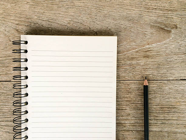 istock Notebook and pencil on old wooden table background textured. 587219714