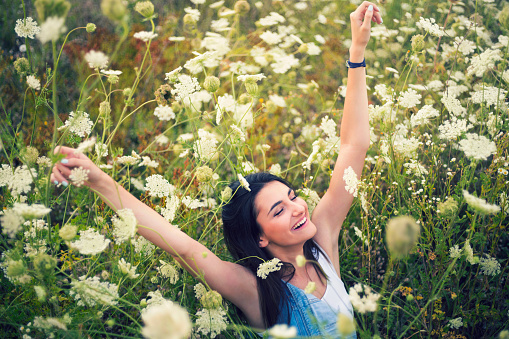 Carefree young woman enjoying a beautiful summer day in the field of wild flowers.