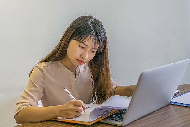 istock Asian office lady checking information on sales reports 587222056