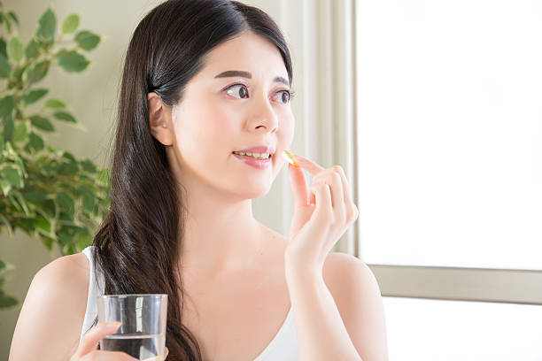 istock young beautiful asian woman eating nutritional supplement pill 587223334