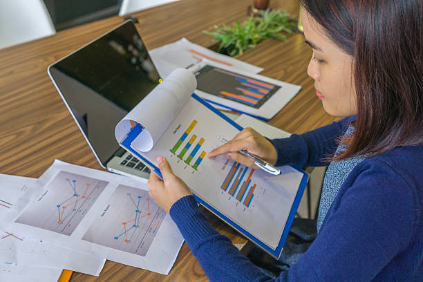 istock Female manager reading report and working with laptop 587223740